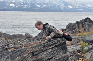 Liam climbing onto a large stump