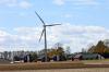A turbine towering over some farm houses